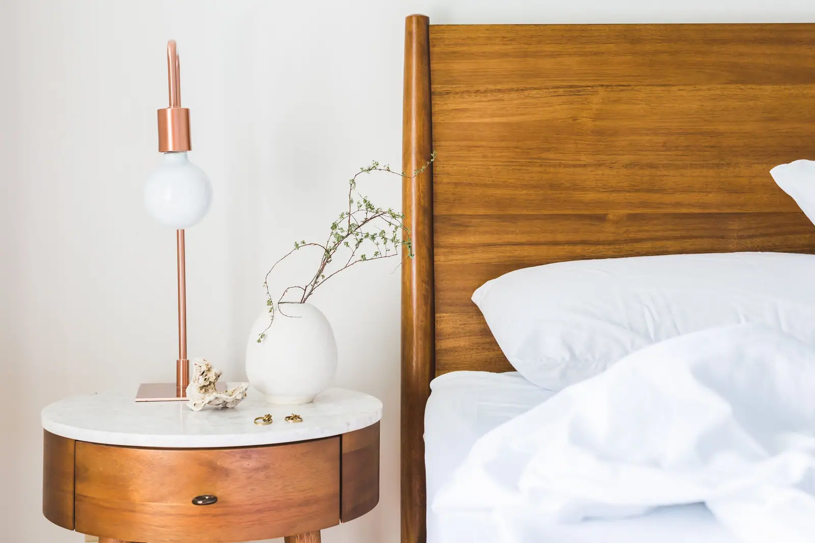 A walnut nightstand with a marble top and a copper reading lamp