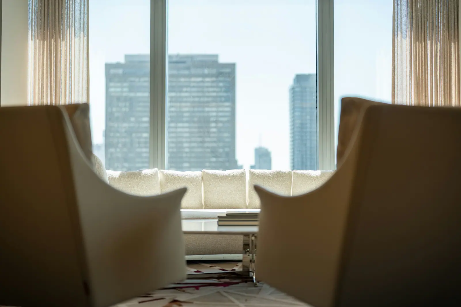 Two cream armchairs facing a tall window over the city