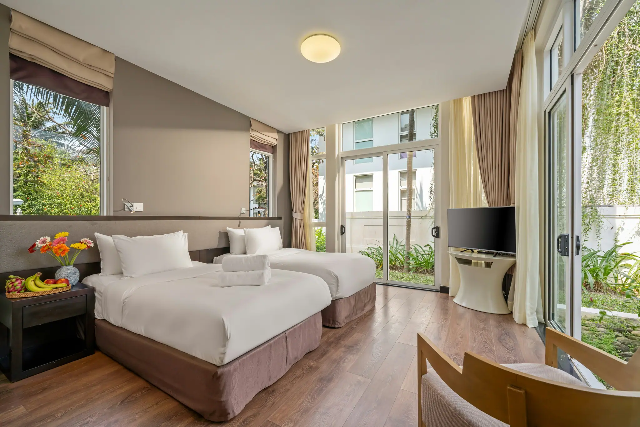 The Deluxe Twin: two made beds beside tall windows and glass doors onto the garden