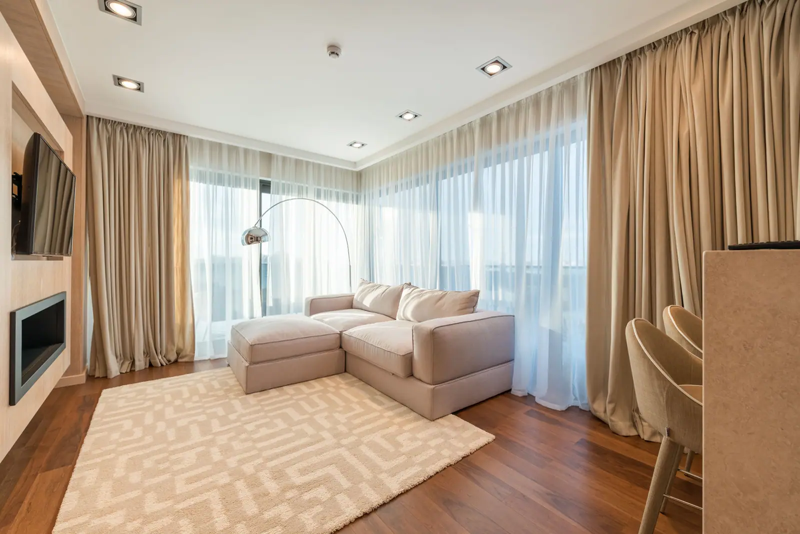 The separate lounge: a linen sofa and ottoman by full-height glass