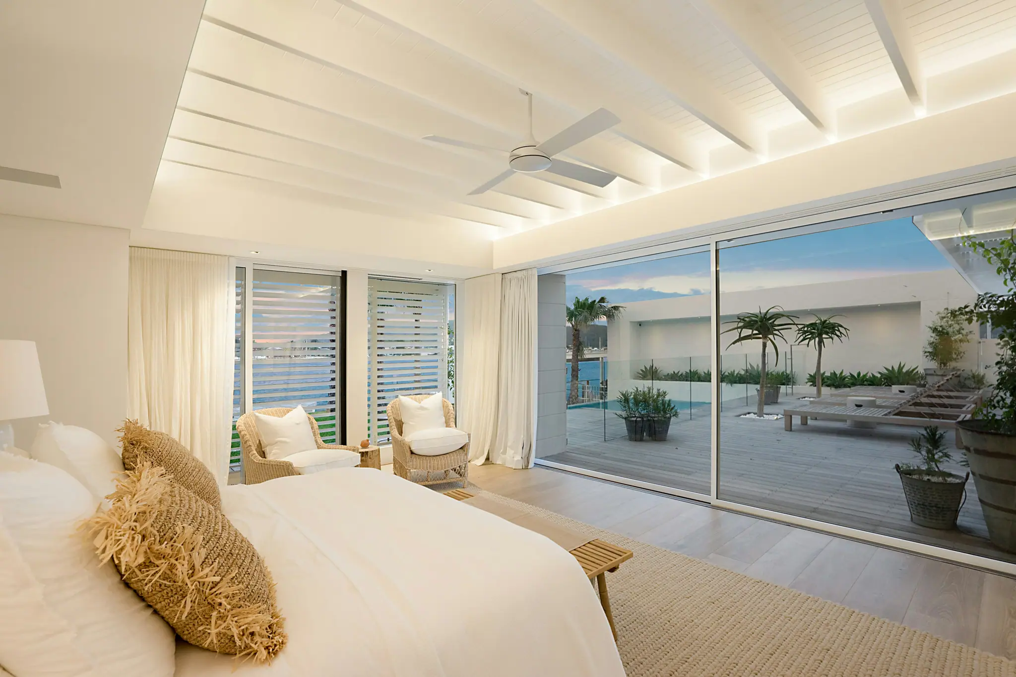 The Premier River View: a white bed facing a wall of sliding glass onto the terrace